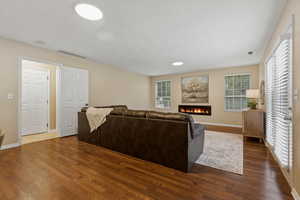 Living area with a lit fireplace, plenty of natural light, and dark wood finished floors
