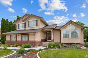 View of front of home with a porch, a front yard, and stucco siding