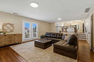 Living room featuring suspended lighting, wood finished floors, and a textured ceiling
