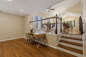 Staircase with wood finished floors, a ceiling fan, and a chandelier