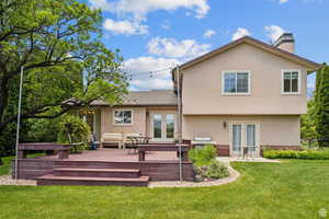 Back of house with french doors, a yard, a deck, a chimney, and stucco siding