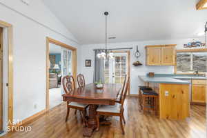 Dining space with lofted ceiling, french doors, light wood-type flooring, and suspended lighting