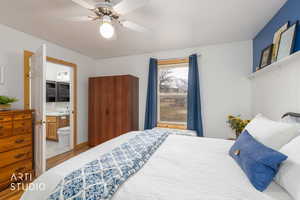 Bedroom featuring light wood-style flooring, ceiling fan, and ensuite bath