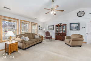 Living room featuring light carpet, vaulted ceiling, and ceiling fan