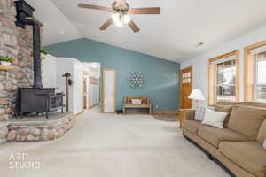 Carpeted living area featuring a wood stove and ceiling fan