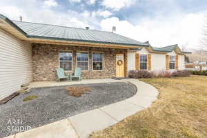 View of exterior entry featuring a yard, stone siding, and a metal roof