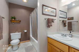Bathroom with vanity, shower / bathtub combination with curtain, and light tile patterned flooring