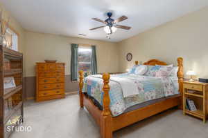 Bedroom with a wainscoted wall, light carpet, and ceiling fan