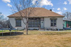 View of front of property with brick siding, a front lawn, a trampoline, and a chimney
