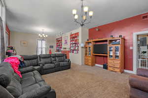 Living room with suspended lighting, carpet flooring, and built in shelves