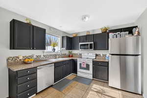 Kitchen featuring stainless steel appliances, dark cabinetry, and light tile patterned flooring