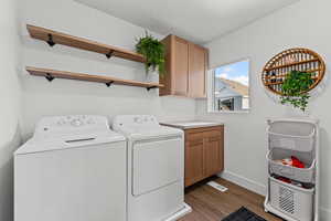 Laundry area with dark wood-style floors, independent washer and dryer, and cabinet space