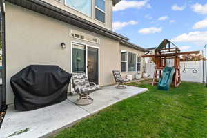 Back of property with stucco siding, a playground, and a patio area
