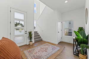 Foyer entrance with light wood-style flooring, stairs, a high ceiling, and recessed lighting