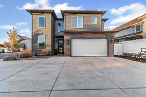 View of front facade featuring driveway, brick siding, and an attached garage