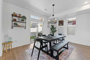 Dining area featuring light wood-type flooring, a chandelier, and a textured ceiling
