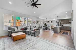 Living area featuring vaulted ceiling, light wood-style floors, recessed lighting, and a ceiling fan