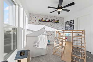 Bedroom featuring carpet floors, wallpapered walls, and a ceiling fan