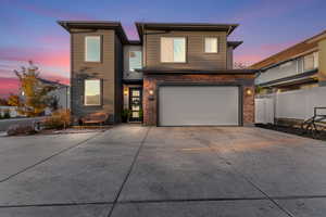 Contemporary house with driveway, brick siding, and an attached garage