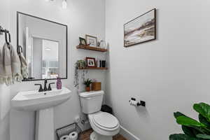 Half bathroom featuring toilet and dark wood-style flooring
