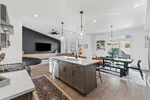 Kitchen with lofted ceiling, light wood finished floors, decorative light fixtures, a kitchen bar, and a kitchen island with sink