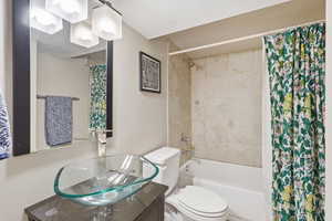 Full bathroom with shower / bathtub combination with curtain, vanity, and a textured ceiling