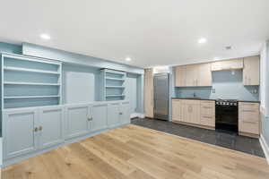 Kitchen with black gas range, dark wood-type flooring, high end refrigerator, open shelves, and recessed lighting