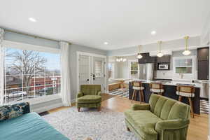 Living room with light wood-style flooring and hanging lights