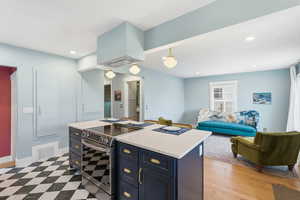 Kitchen featuring electric stove, a center island, open floor plan, pendant lighting, and light stone countertops