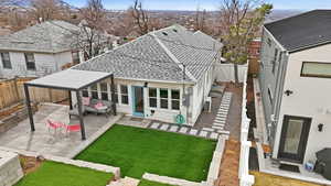 Rear view of house featuring a fenced backyard, roof with shingles, a patio, and a residential view