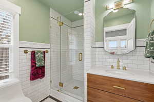 Full bathroom featuring vanity, a shower stall, and tile walls