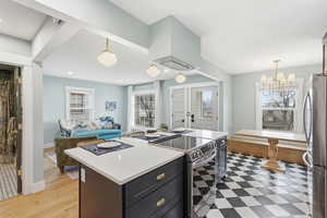 Kitchen with stainless steel appliances, open floor plan, a center island, light stone counters, and a chandelier