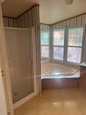 Bathroom featuring a bath, a stall shower, wallpapered walls, and crown molding