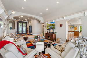 Living room with french doors, arched walkways, recessed lighting, and wood finished floors