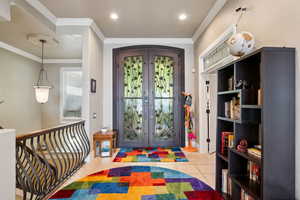 Entrance foyer with french doors, light tile patterned flooring, and crown molding