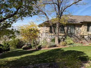 View of side of property featuring a lawn and stone siding