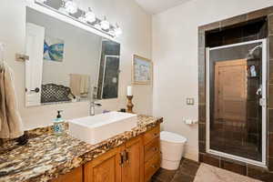 Bathroom with a shower stall, vanity, and dark tile patterned flooring