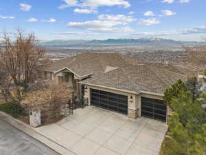 View of front of property featuring a mountain view, a garage, roof with shingles, and driveway