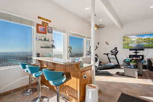 Indoor dry bar with light countertops, beamed ceiling, a ceiling fan, light tile patterned floors, and recessed lighting