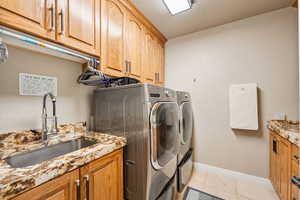 Laundry area with cabinet space, washing machine and clothes dryer, and light tile patterned floors
