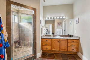 Bathroom with vanity, a stall shower, and a textured wall