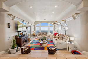 Living area with arched walkways, light wood-type flooring, a textured ceiling, and recessed lighting