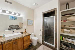 Full bathroom with vanity, a stall shower, and dark tile patterned flooring
