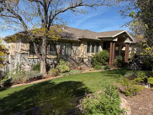 Single story home featuring a front lawn and stone siding