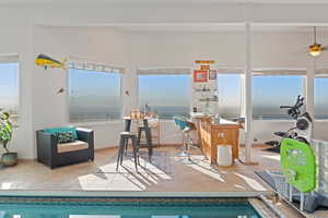 View of swimming pool featuring ceiling fan, a sunroom, and a water view