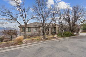 View of front of house featuring stone siding and roof with shingles