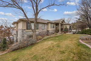 View of side of home featuring a yard, stone siding, and stucco siding