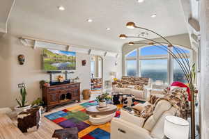 Living area featuring healthy amount of natural light, a chandelier, vaulted ceiling, and arched walkways