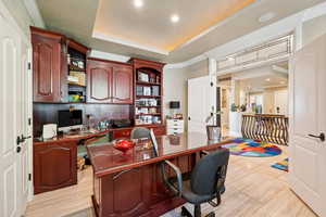 Office with ornamental molding, built in study area, recessed lighting, light wood-type flooring, and a tray ceiling