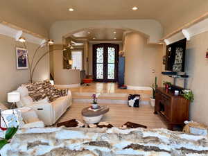 Living room featuring french doors, crown molding, recessed lighting, and arched walkways